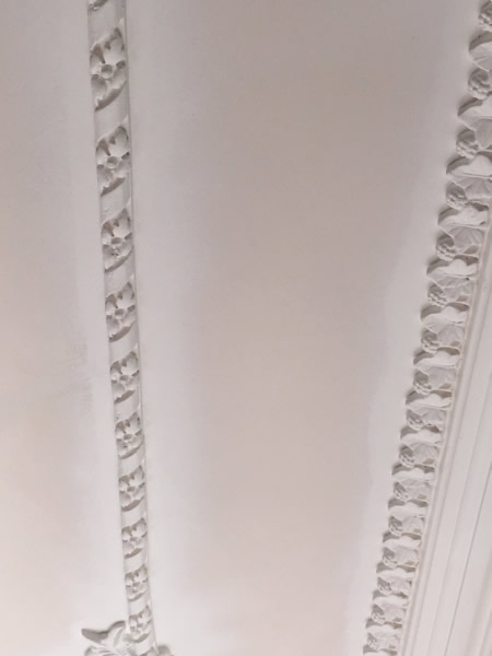 Repainted plaster ceiling border alongside leaf-decorated cornice at Clissold Crescent.